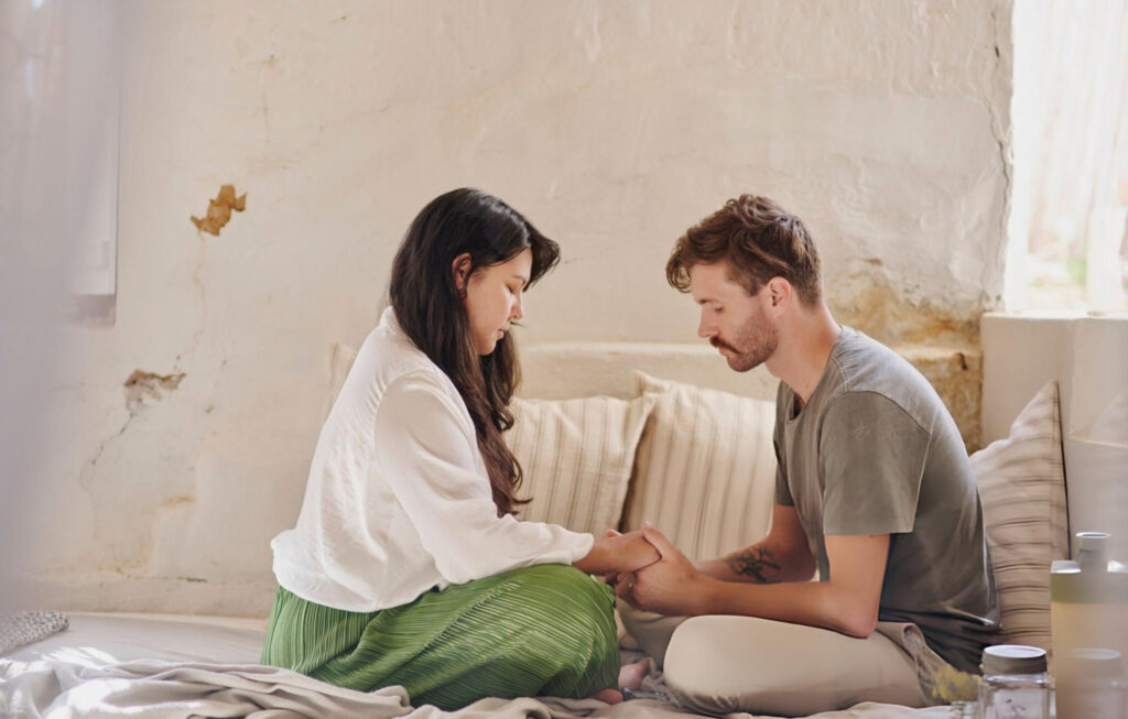 A man and woman holding hands praying together