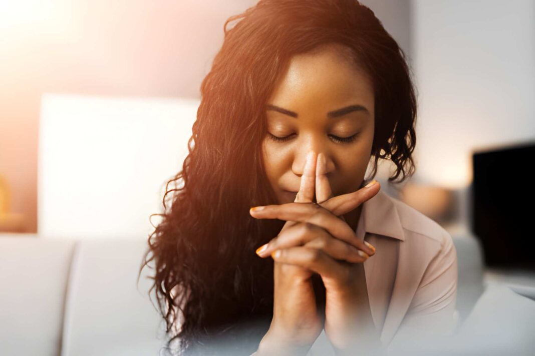 A girl praying with both hands clapped together and eyes closed