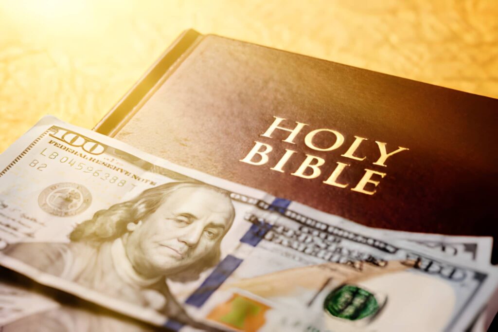 A closed copy of the Holy Bible has several US banknotes resting on it. 