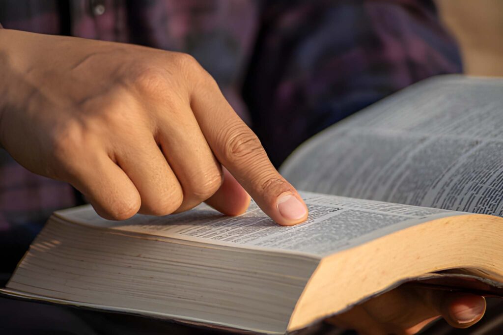A Hand placing an index finger on a bible - Image: iStockphoto