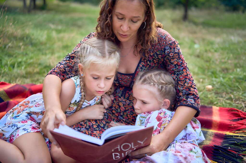 A mother and her two daughters reading the holy bible.