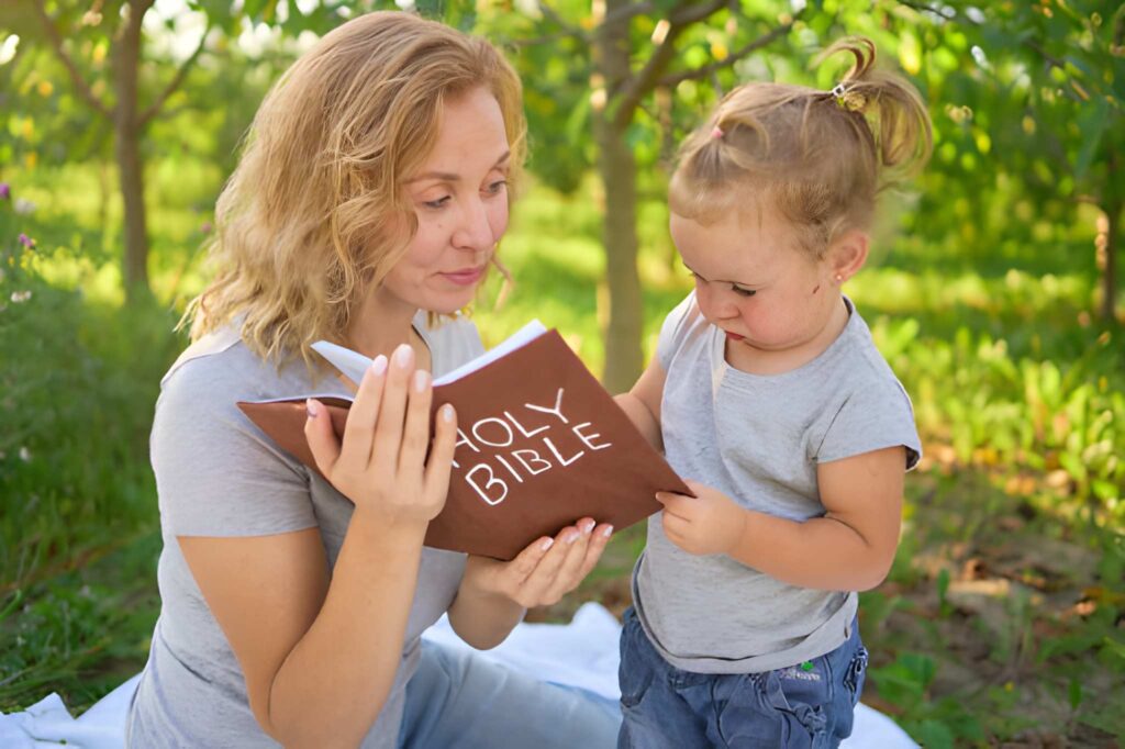 A mother reading the holy bible to her daughter in the garden