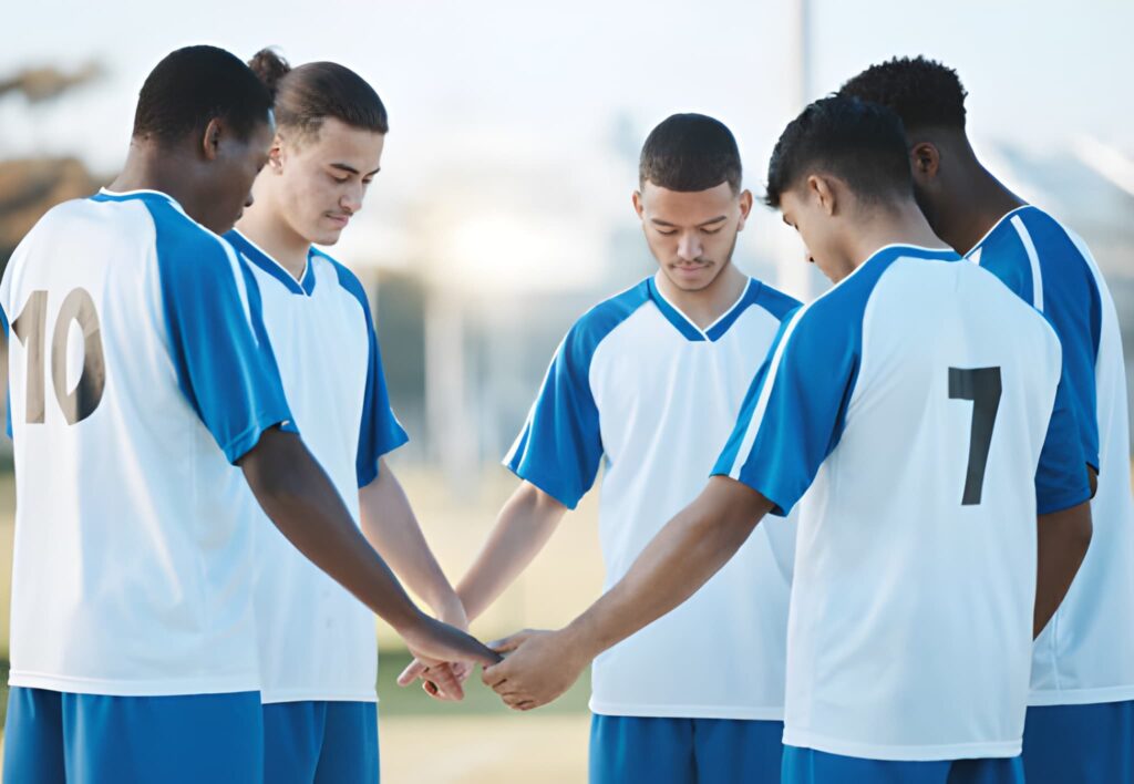 Athletes holding hands, slightly bowing down, praying before an exercise