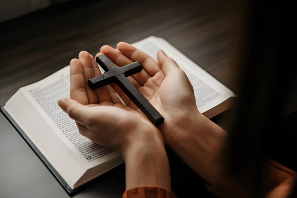 Woman sitting and studying the scriptures with wooden cross in her hands