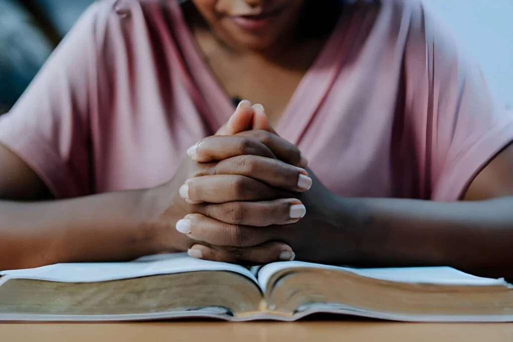 Woman praying with the bible on the table 
