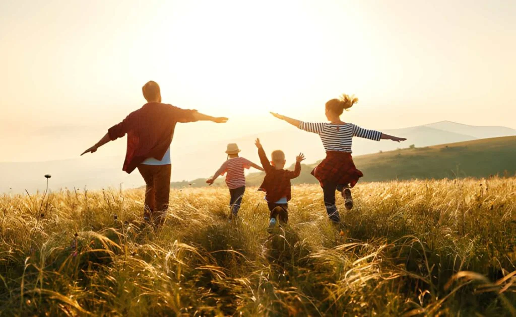Happy family: mother, father, son and daughter playing on the sunset