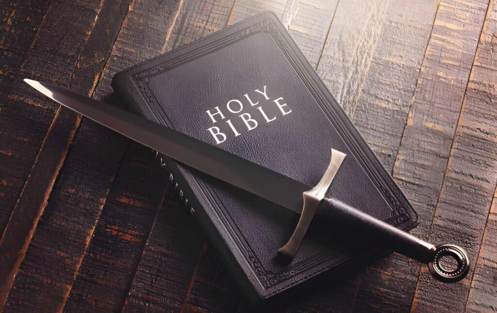 A Bible and a Sword on a Dark Wooden Table