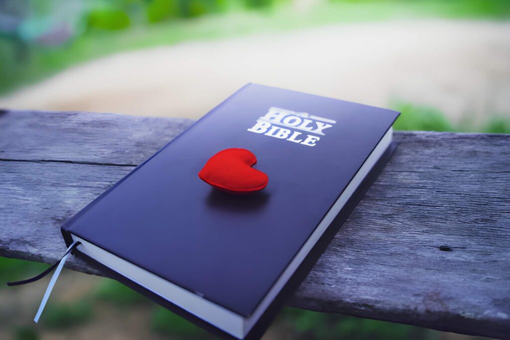 Red heart with bible on wooden table
